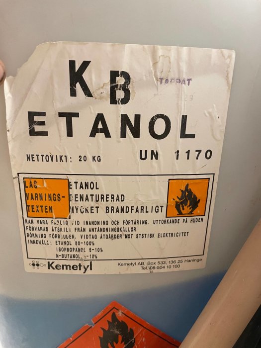 Etikett på en dunk med texten "KB Etanol", varningsmärkningar och innehållsförteckning för etanolblandning.
