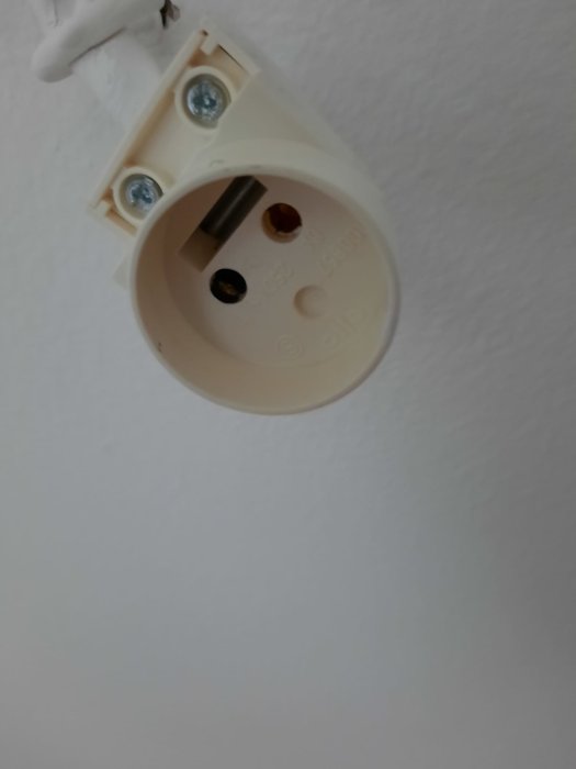 Takuttag för lampa med synliga skruvar och strömkontakter i oskarp vit bakgrund.