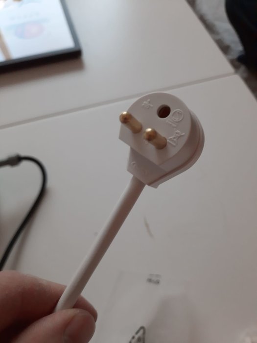 Närbild på en oinkopplad vit taklampkontakt med rund skaft och guldpläterade stift.