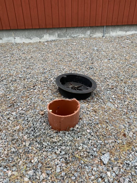 Avloppsledning med en öppen inspektionskanal och lös lock bredvid på grusmark.
