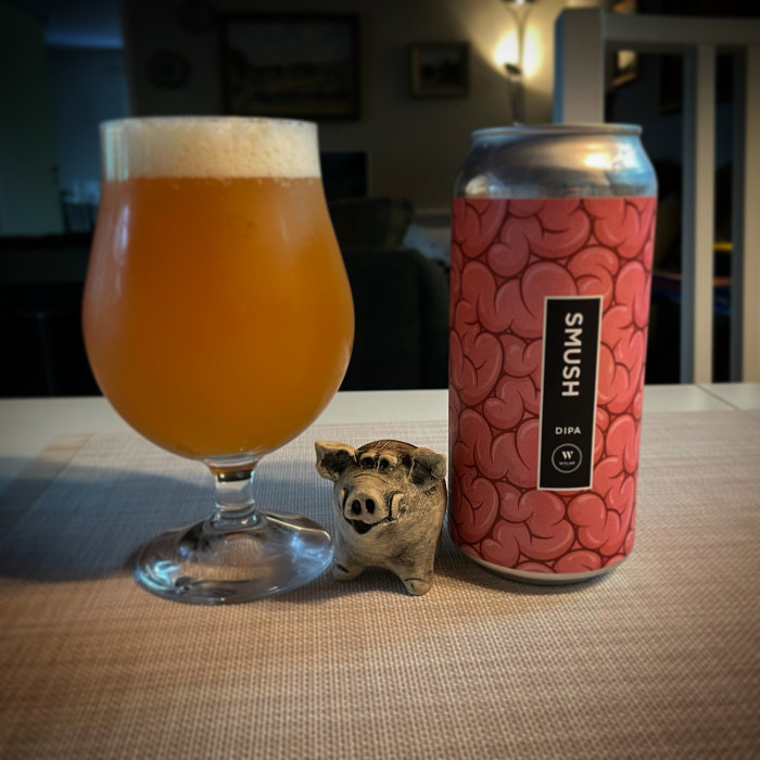 Ölglas bredvid burk med etikett "SMUSH" och en liten prydnadsgris på ett bord.