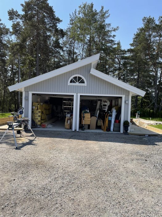 Alt: Öppet garage med diverse byggmaterial och verktyg, indikerar behovet av städning.