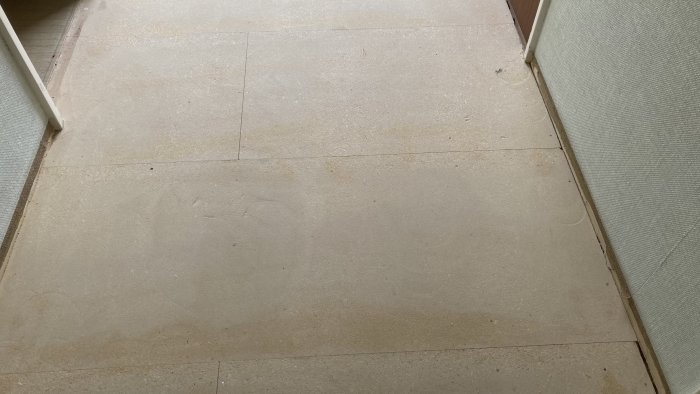 Plywood floorboards in a hallway, some whole, some cut, with visible seams and potential structural concerns.
