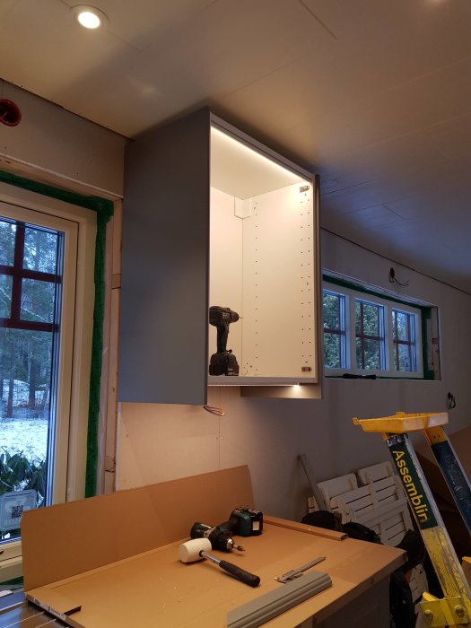 Infälld bänkbelysning under väggskåp i en under-renovering köksmiljö med verktyg på arbetsbänken.