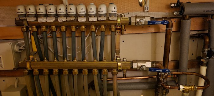Installation av flera uppmärkta rörledningar och ventiler på en vägg, en del av ett värmesystem.
