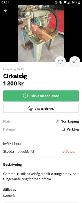 Radialarmssåg på robust stativ i en verkstadsinställning med röd bil i bakgrunden.