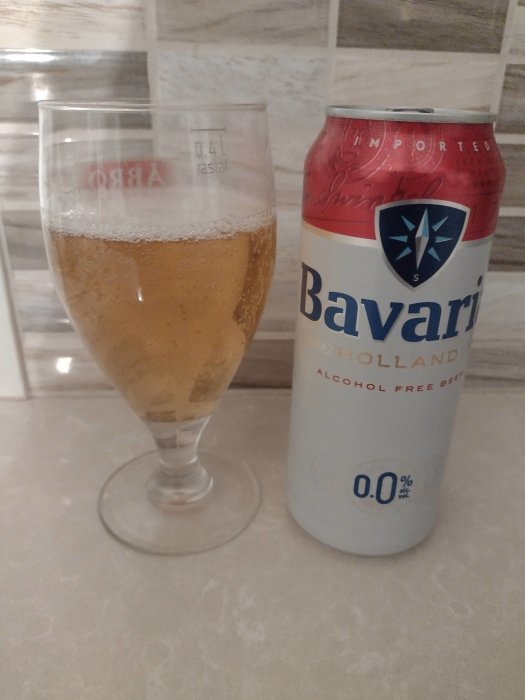 Ölglas med alkoholfritt Bavaria öl bredvid en tom Bavaria burk.