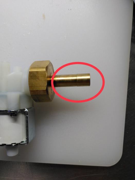 Mässingsdel med utstickande axel markerad med röd cirkel på vit bakgrund för storleksbedömning.