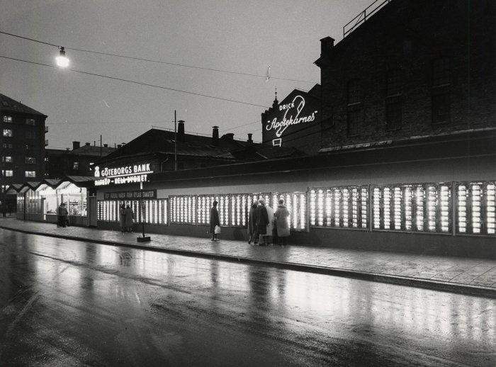 Svartvit bild av världens största varuautomat med 1.500 fack på Götgatan i Stockholm på kvällen.