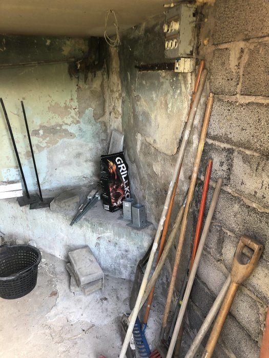 Gammalt pannrum med exponerade rör och sliten betongvägg, verktyg och byggmaterial på golvet.