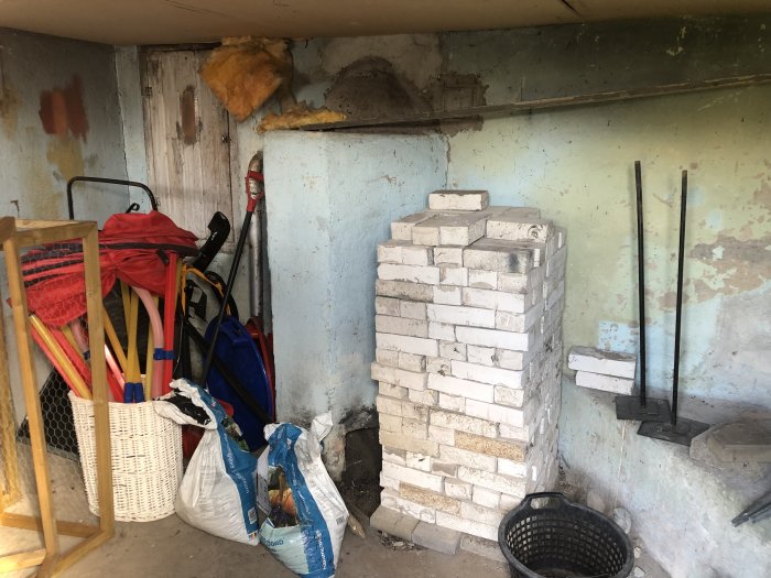 Gammalt pannrum med vita tegelstenar, sportutrustning och renoveringsmaterial.