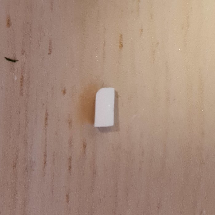 Liten vit plastbit på en beige vägg som hindrade en strömbrytare från att fungera korrekt.