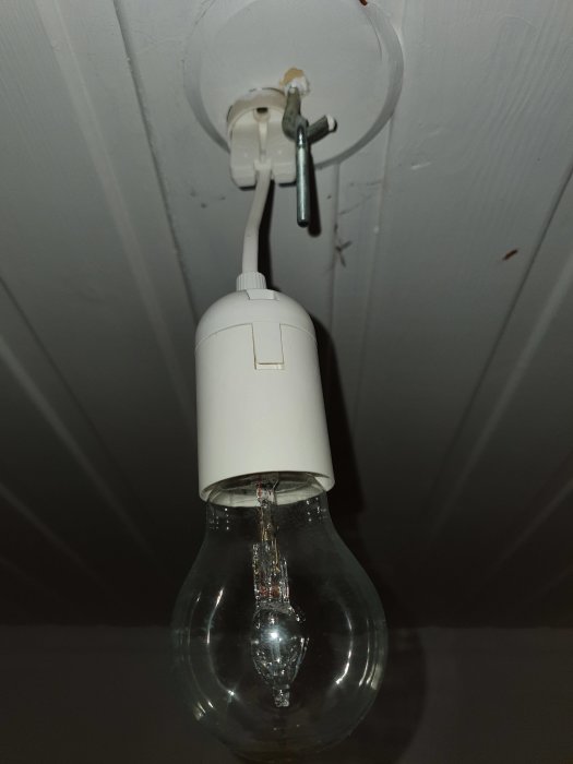 Enkel upphängning med elsladd och glödlampa hänger från taket utan sockerbit.