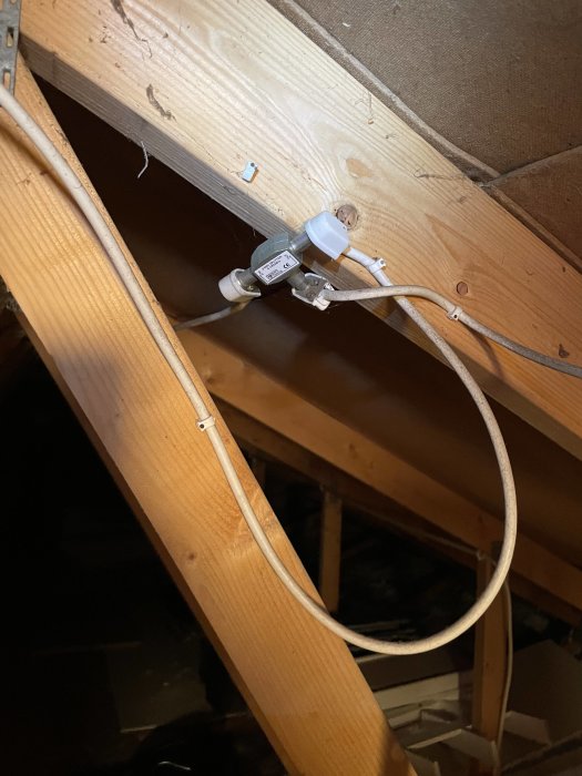 Kabelinstallation med skarvdon på vind, där kabel delas upp i två ledningar.