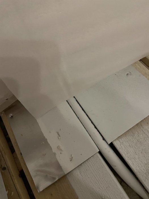 Golvbit nära vägg med möjlig vattenburen värme, metallskiva som skydd vid sågning.