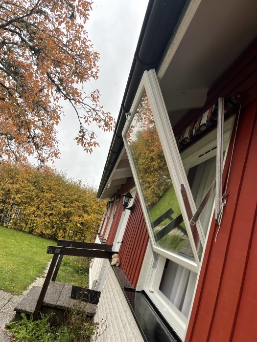 Fönster som inte kan öppnas helt och slår i fasaden på rödmålat hus med vita karmar.