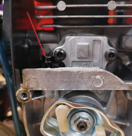 Närbild på en trimmermotor med en pil som pekar mot en åtdragen skruv och en löstagbar kabel från avstägningsknappen.