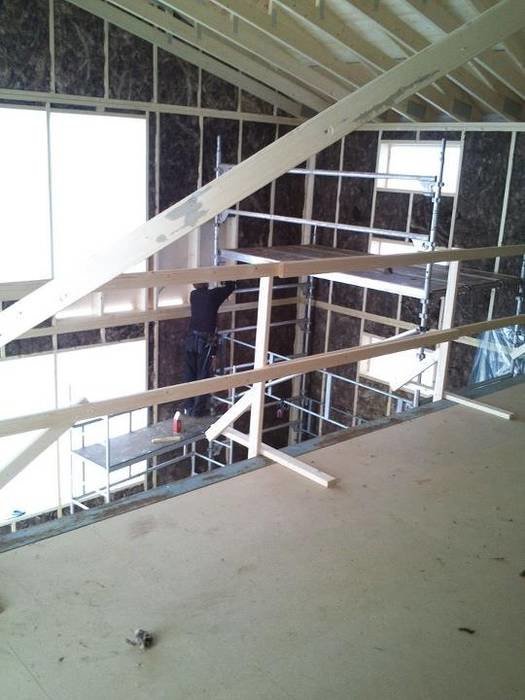 Interiörbild av ett fritidshus under konstruktion med synliga takstolar och väggreglar.