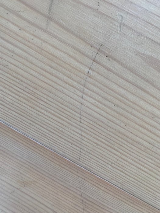 Vitvaxat furugolv med synliga slitage och repor, behov av underhåll och omvårdnad.