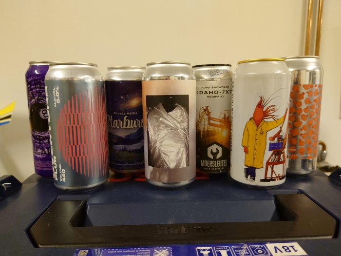 Rad av ölburkar med varierande färgglada etiketter på en blå våg, symboliserar ett nyligen mottaget paket.