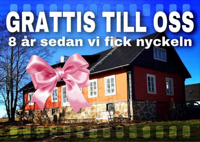 Traditionellt rött hus med stenfot och texten "GRATTIS TILL OSS 8 år sedan vi fick nyckeln" och en stor rosa rosett.