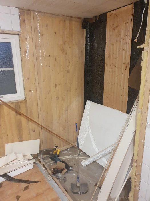 Hörn av ett pågående byggprojekt med isolering och OSB-skivor ovanpå träspont samt byggmaterial på golvet.