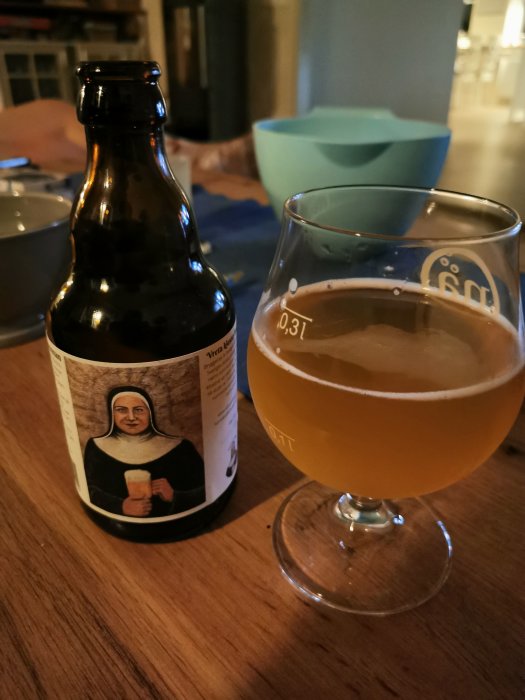 Ölflaska från Vreta Klosterbryggeri med etikett "Den blonda nunnan" och ett glas med öl bredvid.