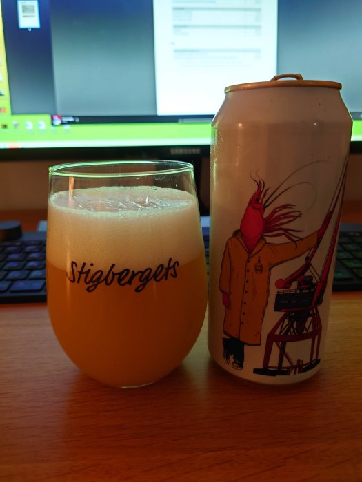 Ölglas från Stigbergets och ölburk från Fermenterarna på ett skrivbord framför en datorskärm.