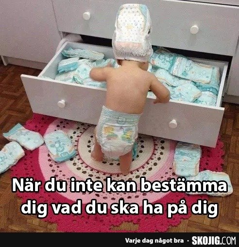 Ett litet barn står framför en öppen låda full med blöjor, bär en blöja och en blöja på huvudet, humoristiska toner.