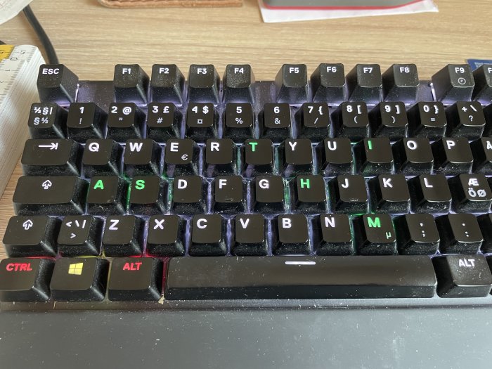 Närbild av ett mekaniskt tangentbord med RGB-belysning och upplysta bokstäver.
