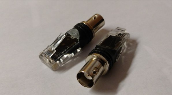 En RJ45-nätverkskontakt och en coaxial-tv-kabelkontakt på ett vitt underlag.