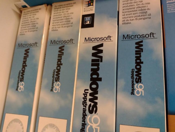 Flera lådor med Microsoft Windows 95-uppgraderingspaket staplade i en hylla.