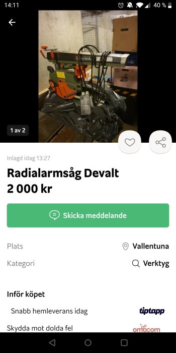 Radialarmsåg av märket Dewalt placerad i ett garage med betongväggar och diverse föremål i bakgrunden.