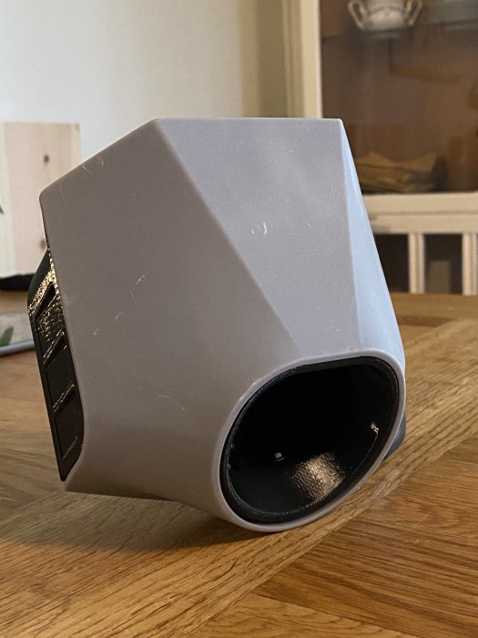 Grå PVC-koppling för VVS-installation liggande på ett träbord.