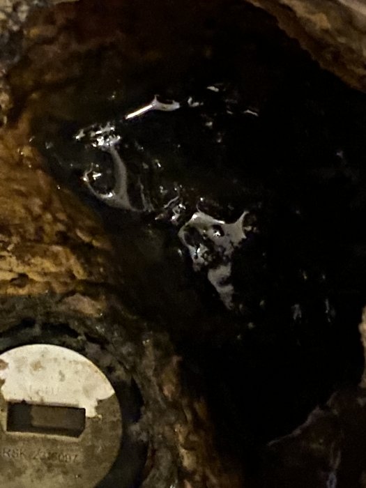 Vattenläcka med synligt vatten och avlagringar runt ett RSK-numrerat rör i ett mörkt utrymme.