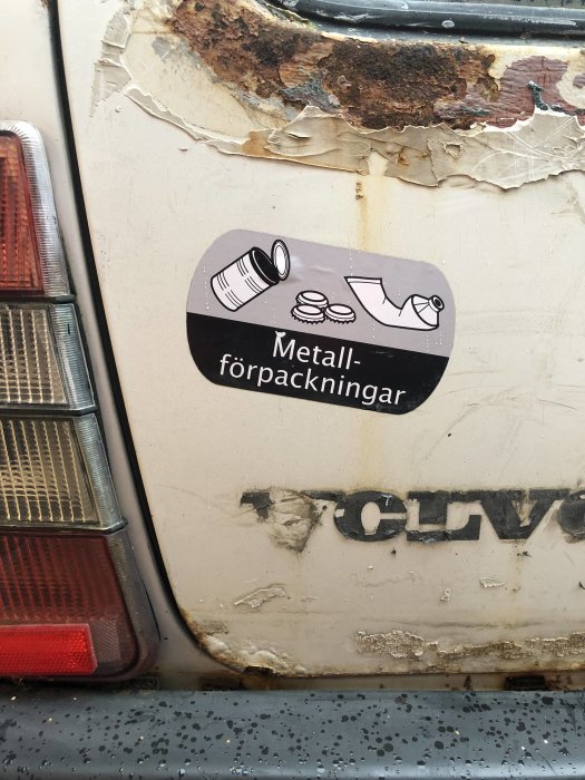 Dekal på en bil med texten "Metallförpackningar" och bilder av en konservburk, kapsyler och en aluminiumburk.