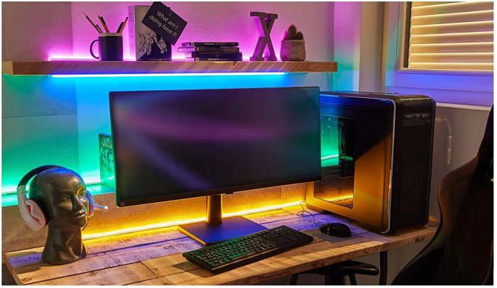 Skrivbordsmiljö med RGB-belysning, dataskärm, tangentbord, speldatorchassi och prydnader.