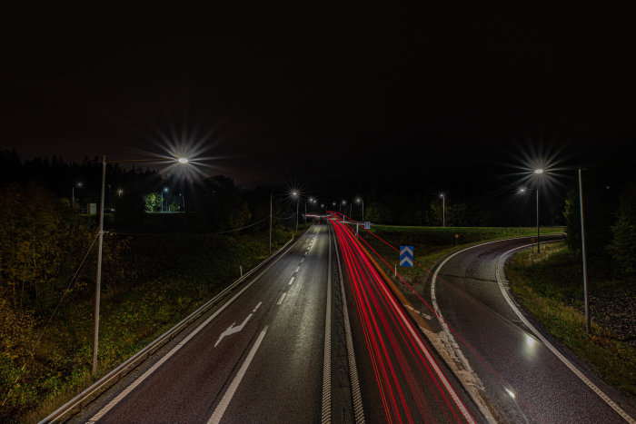 Lång exponering av trafikerad väg på natten med ljusspår från bilarnas lampor.