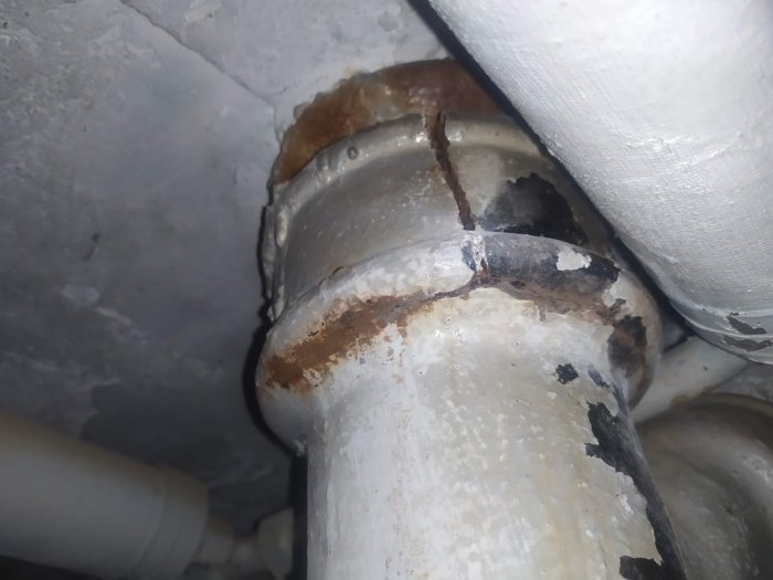 Gamla gjutjärnsrör med rost och spricka vid sammanfogning, inga vätskor synliga.