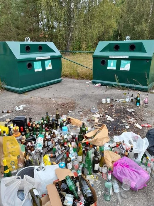 Överfulla glasåtervinningsbehållare med tomglas och sopor runtom på marken.