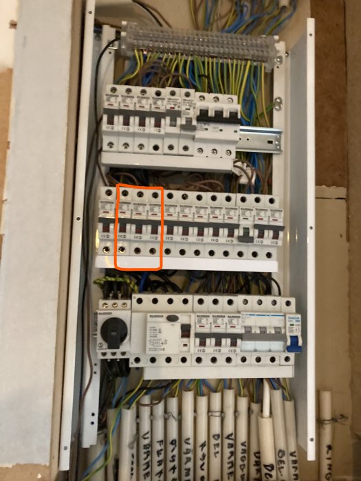 Öppen elcentral med synliga säkringar och svetsmärken markerade med röda pilar.