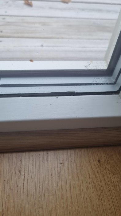 Närbild på fönsterkarm med eventuell vattenskada och kondens mellan tvåglasfönster och träram.