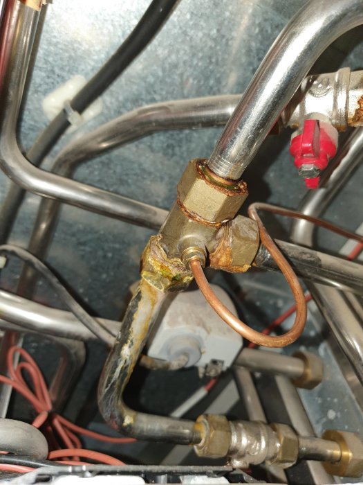 Läckande rörkoppling med gröna avlagringar inuti en mekanisk anordning.