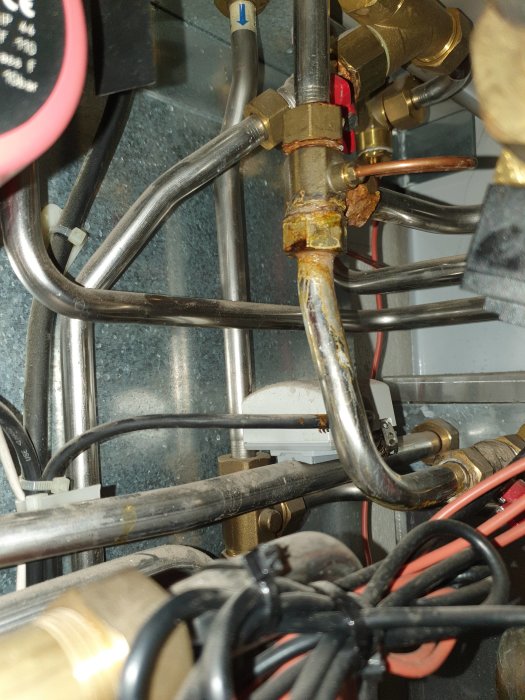 Korroderad koppling med grön vätskeläckage i rörsystem.