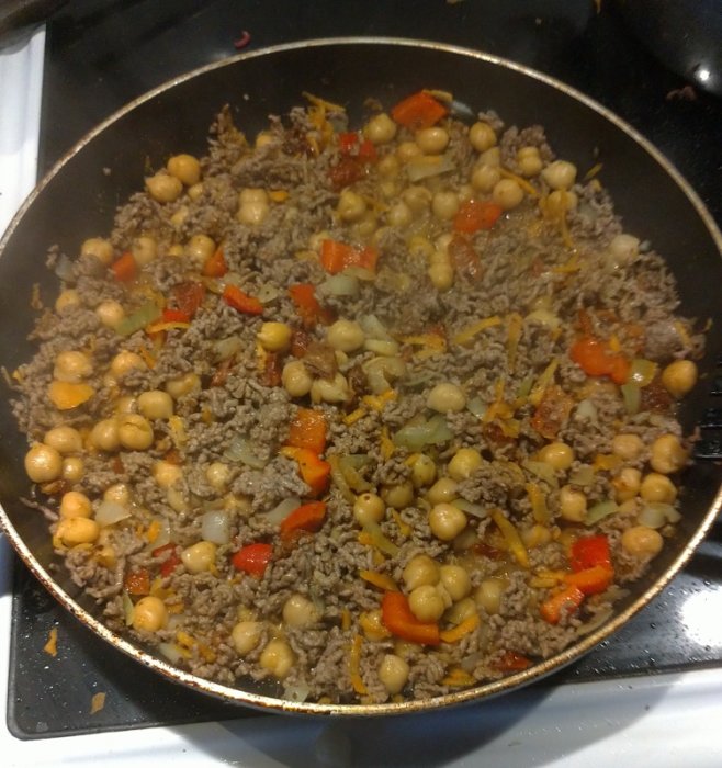 Hemlagad köttfärsrätt med kikärter, hackad paprika, morot och soltorkade tomater i en stekpanna.