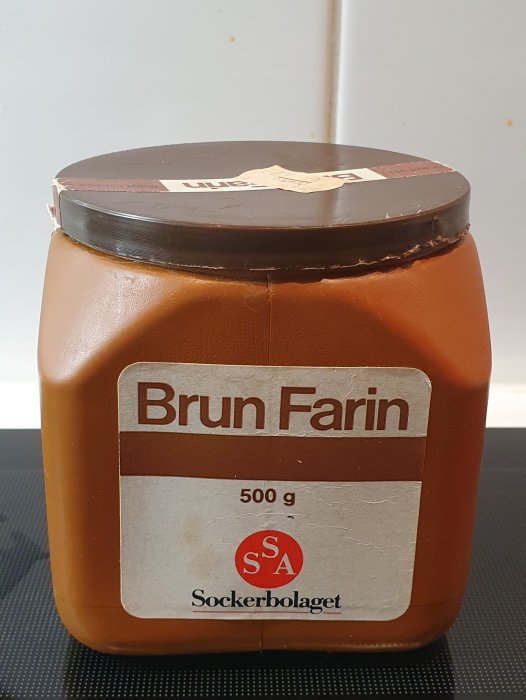 Gammal brun farinsockerburk från Sockerbolaget som står på en bänk.