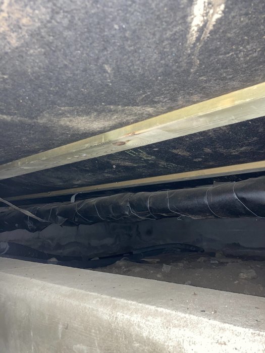 Oisolerat golvbjälklag och rörledningar under tillbyggnad av ett hus.