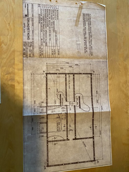 Byggritning upplagd på ett träbord med markerad sektion som är borttagen.