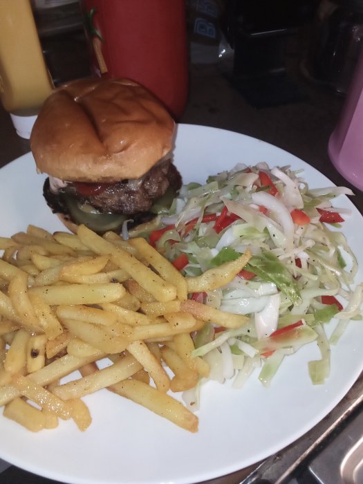 Kalvfärsburgare med inlagd gurka i bröd, kryddade strips och italiensk sallad med vitkål och paprika.