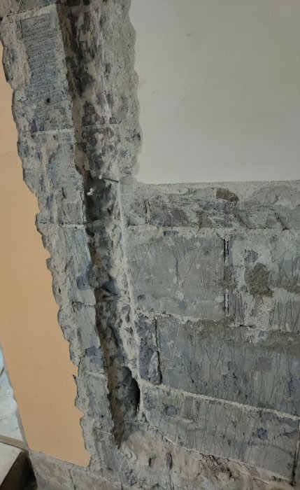 Vägg under renovering med synligt armeringsnät och pågående putsarbete.